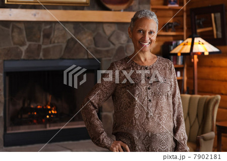 Mature woman smiling by fireplace, portrait 7902181