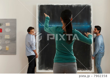 Art dealer arranging hanging of oil painting in gallery 7902358