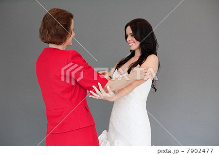 Daughter trying on wedding dress, embracing mother 7902477