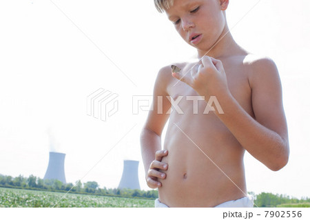 Boy holding butterfly on little finger with nuclear power station in background 7902556