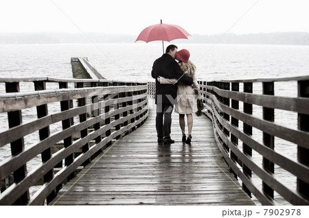 Couple kissing on wooden pier in rain Couple kissing on wooden pier in rain 7902978