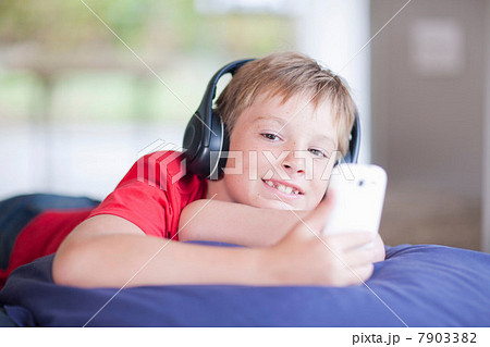 Boy on bed listening to music on smartphone 7903382