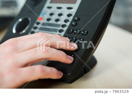 Office worker dialling on a landline phone 7903529