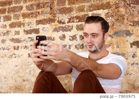Man using cell phone by brick wall Man using cell phone by brick wall 7903975