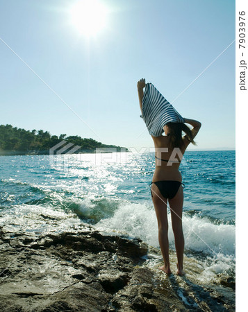 Young woman taking off t-shirt by the sea Young woman taking off t-shirt by the sea 7903976