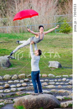 Mid adult dancers performing with red umbrellas in stone circle 7904033