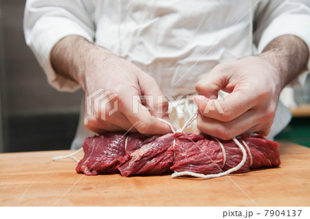 Butcher tying beef tenderloin with string 7904137