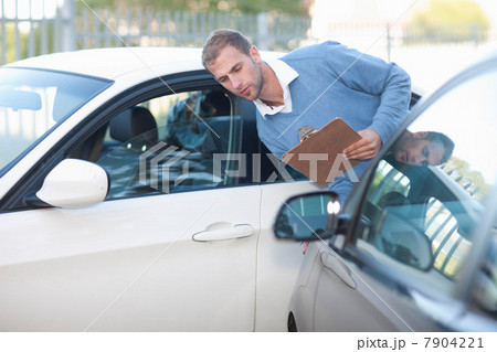 Man assessing damage on car after car accident 7904221