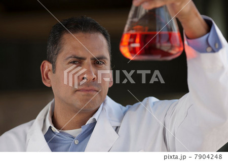 Mature scientist looking at liquid in volumetric flask Mature scientist looking at liquid in volumetric flask 7904248