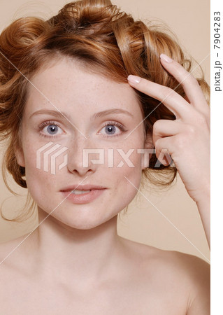 Young woman with curly red hair biting lip Young woman with curly red hair biting lip 7904283