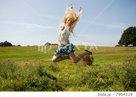 Young woman in a field, jumping in the air 7904319