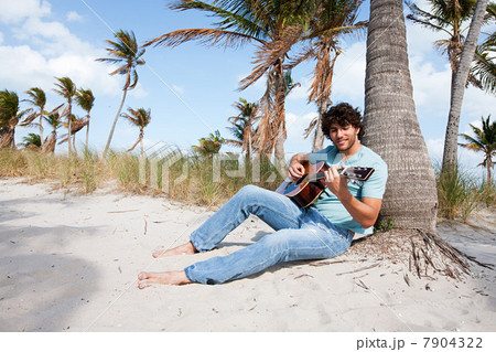 Young man playing guitar on beach, portrait 7904322