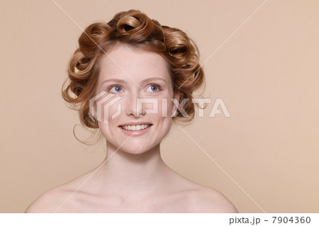 Young woman with curly red hair looking away and smiling Young woman with curly red hair looking away and smiling 7904360