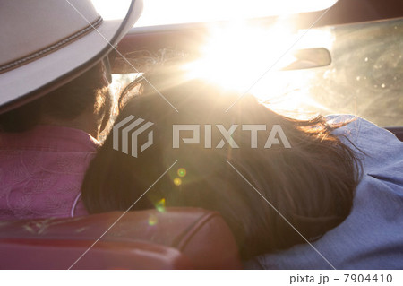 Woman resting head on boyfriend's shoulder as he drives in sunlight 7904410