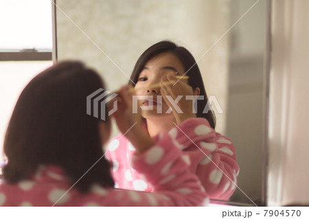 Young woman applying makeup using bathroom mirror Young woman applying makeup using bathroom mirror 7904570