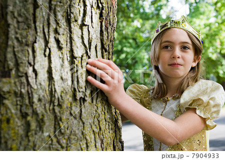Girl dressed up as queen touching tree trunk Girl dressed up as queen touching tree trunk 7904933