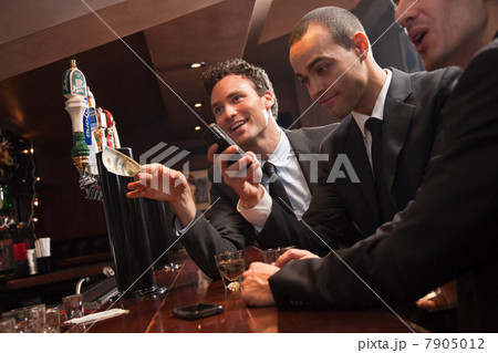 Three businessmen getting drinks at a bar 7905012