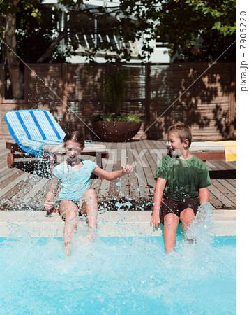 Boy and girl splashing in swimming pool 7905220