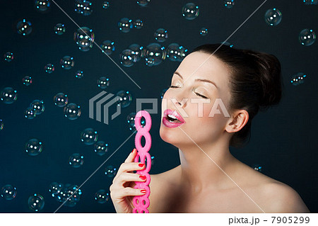 Young brunette woman blowing bubbles with bubble wand 7905299