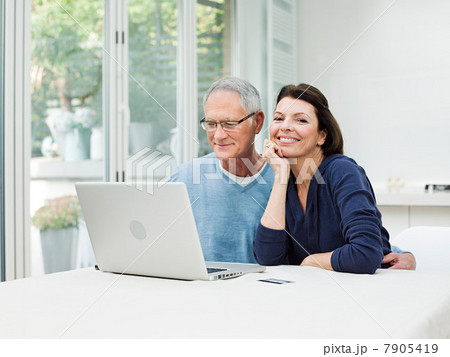 Mature couple using laptop with credit card 7905419