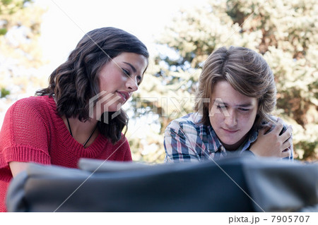 Teenage couple studying on picnic table in park Teenage couple studying on picnic table in park 7905707
