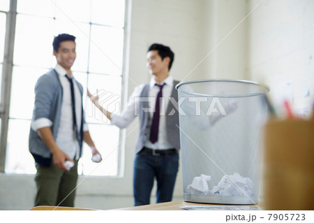 Two young men using waste paper bin for target practice Two young men using waste paper bin for target practice 7905723