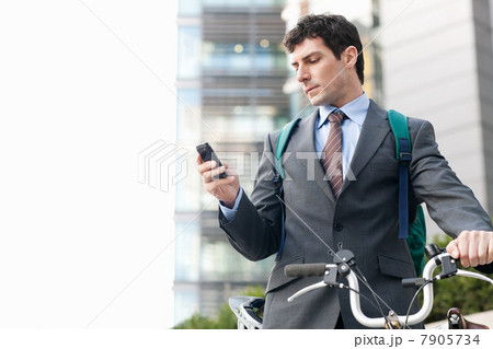Mid adult businessman with bike using cellphone Mid adult businessman with bike using cellphone 7905734