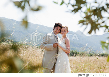 Newlyweds embracing in field 7905855