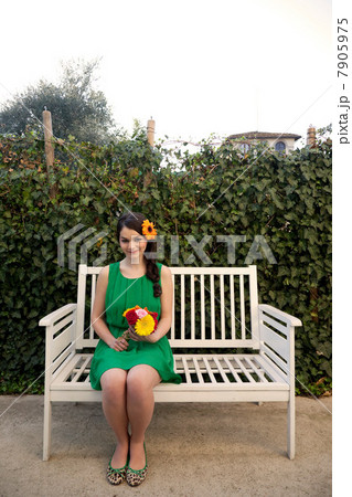 Woman on bench holding flowers 7905975