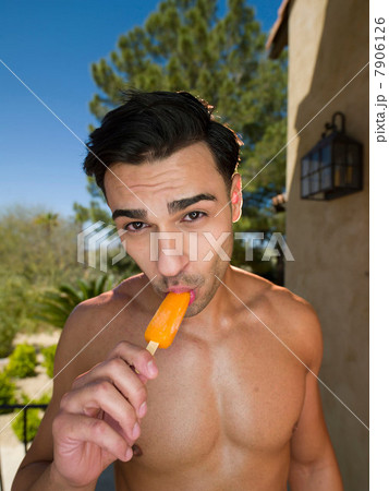 Young man eating ice lolly on vacation, portrait 7906126