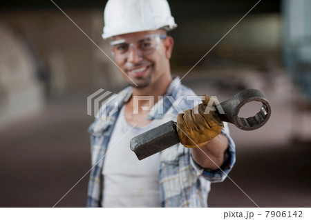 Mid adult construction worker wearing hard hat and holding wrench, portrait 7906142