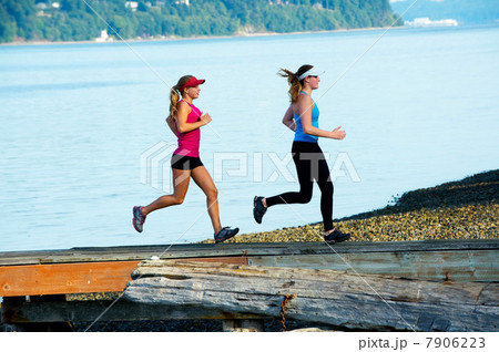 Teenage girls running together on beach 7906223