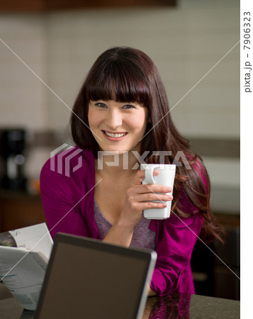 Young woman holding coffee mug in kitchen, smiling 7906323