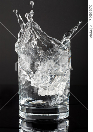 Ice cube splashing in a tumbler of gin and tonic 7906670