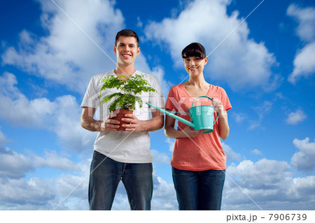 Couple in field with watering can and plant Couple in field with watering can and plant 7906739