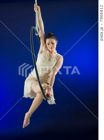 Aerialist poised on hoop against blue background Aerialist poised on hoop against blue background 7906812