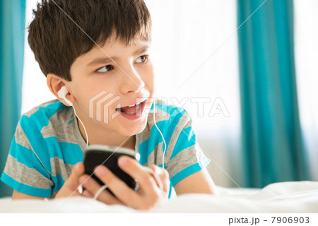 Boy listening to mp3 player on bed 7906903