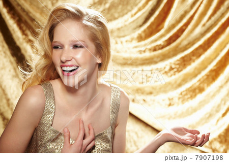 Candid portrait of young woman in front of gold curtain 7907198