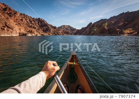 Man rowing canoe on still rural lake 7907374