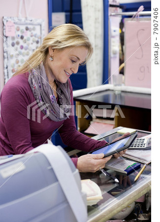Cashier using tablet computer in store 7907406