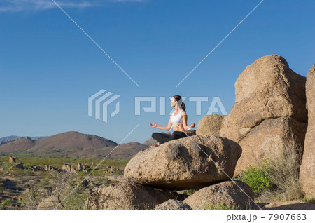 Woman in lotus position on boulder 7907663