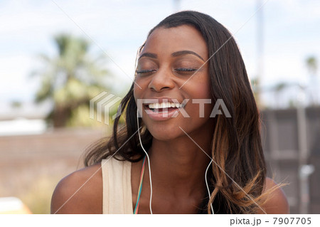 Woman listening to earphones outdoors Woman listening to earphones outdoors 7907705