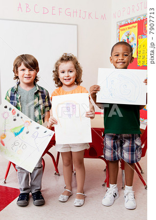 Three children holding pictures they have drawn 7907713