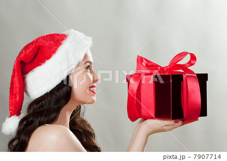 Young brunette woman wearing Santa hat with Christmas present 7907714
