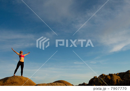 Young woman standing in desert with arms open Young woman standing in desert with arms open 7907770