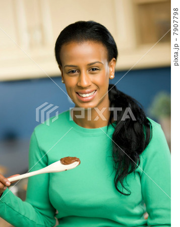 Young woman holding spoon and smiling, portrait 7907798