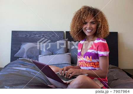 Mid adult woman sitting on bed using laptop, portrait 7907964