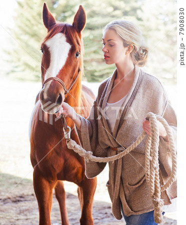 Young woman looking after horse on farm 7908030