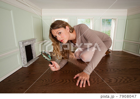 Young woman in small room with magnifying glass 7908047