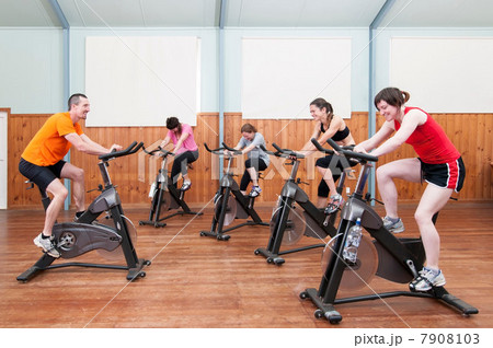 Male instructor leading female spinning class Male instructor leading female spinning class 7908103
